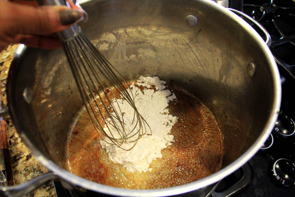 Once all the browned bits are released, and the butter is hot, add the flour and whisk to combine, breaking up any lumps. Work quickly here.