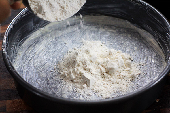 add some flour and shake it around until the entire inside of the cake pan is coated. 