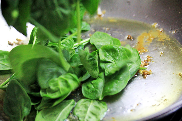reduce the heat to medium, and don't scrape up what's left from the fish, leave it in there. maybe add another tablespoon or so of oil if needed, but start to pile the spinach into the pan.