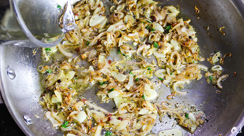 pouring wine in sautéed shallots and garlic