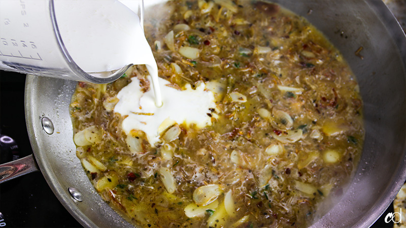 pouring heavy cream into reduce wine sauce