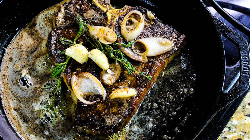 basting porterhouse steak with butter and herbs