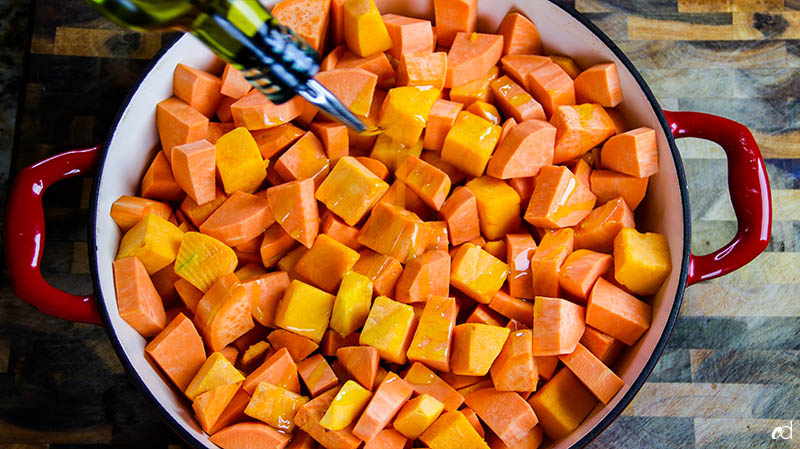 adding olive oil to sweet potatoes and butternut squash