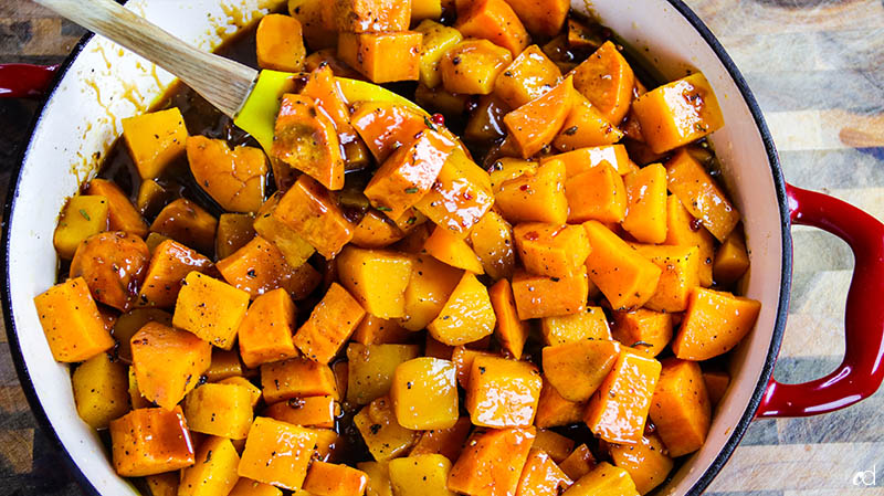 tossing roasted sweet potatoes and butternut squash with savory caramel