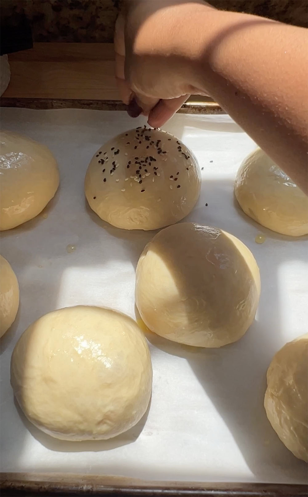 sprinkling sesame seeds on hamburger buns